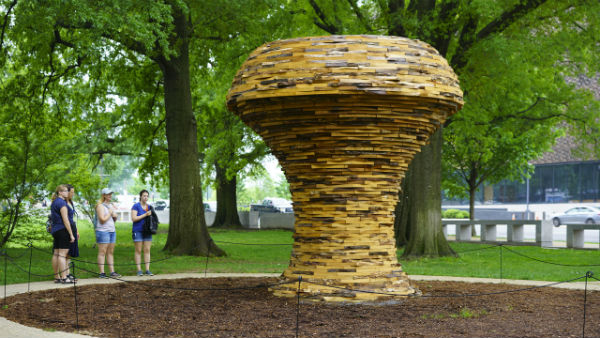 A large, wooden mushroom-shaped sculpture in a garden