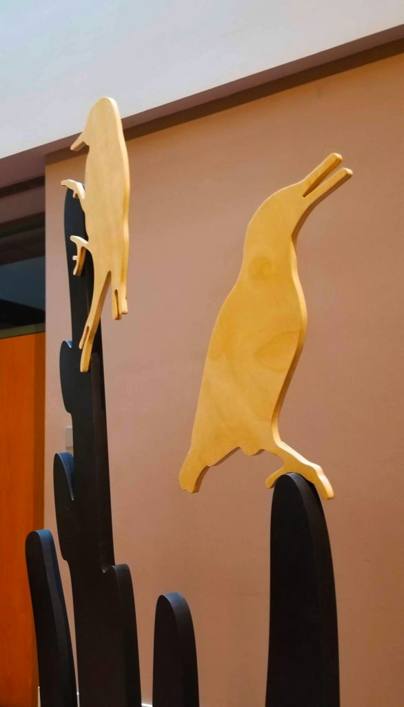 Pale wood cutouts in the shape of birds perched on top of black cutouts in the shape of cacti
