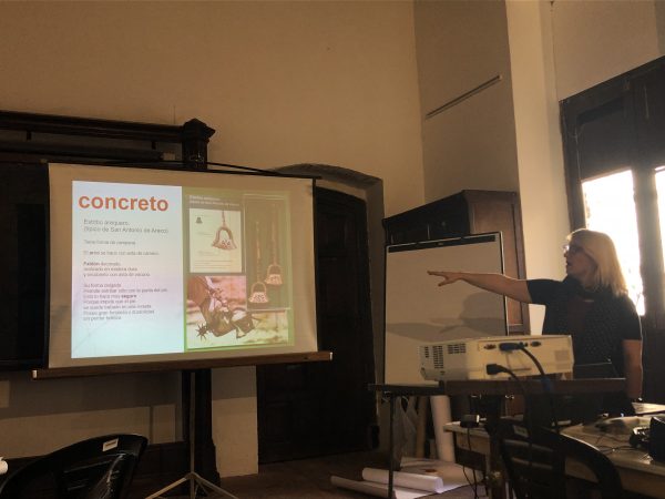 a woman points to a screen with the Spanish word "concreto" and tips for writing Spanish museum texts