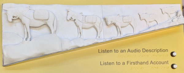 A white 3D model showing five mules carrying packages. Buttons below the model are labeled "Listen to an Audio Description" and "Listen to a Firsthand Account."