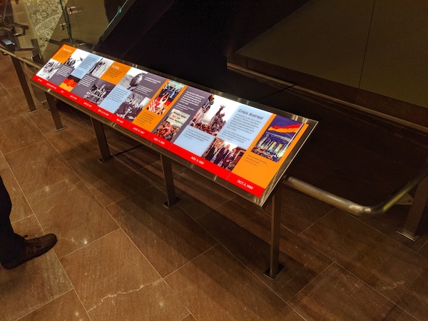 An illuminated red and orange reader rail with a series of dates and images of the Berlin Wall