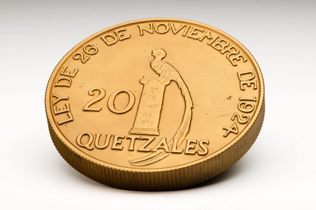 A replica of a 20-quetzales coin made in Guatemala in the 1920s. The front design is inspired by the tail feathers of the quetzal bird, which served as currency in Mexico and Central America under the Aztec empire.