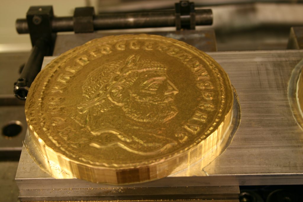 A brass replica of the Roman follis coin before the patina was applied.