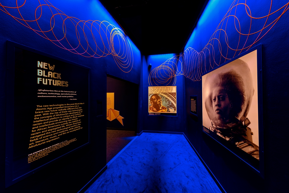 A hallway lit with blue light containing two images of Black people in spacesuits, the title "New Black Futures," and a spiral design.