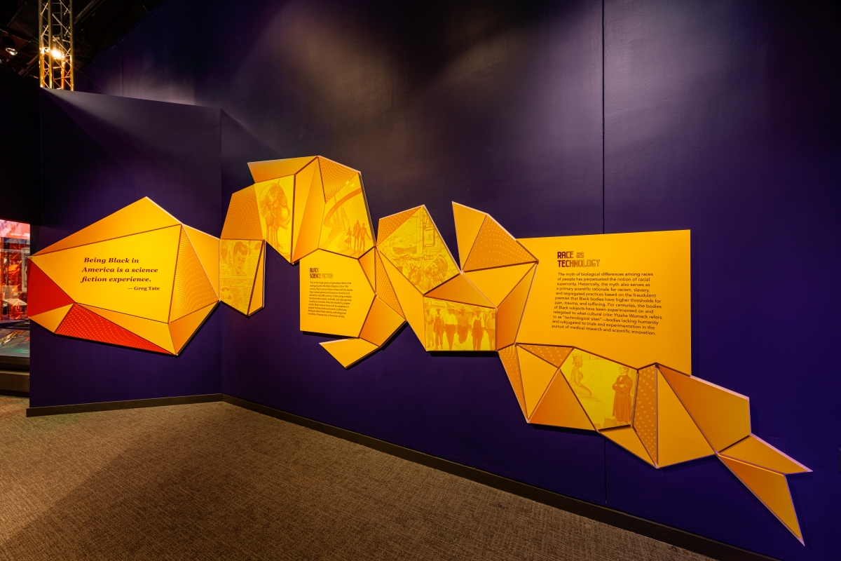 A purple wall lined with yellow geometrically shaped graphic panels.